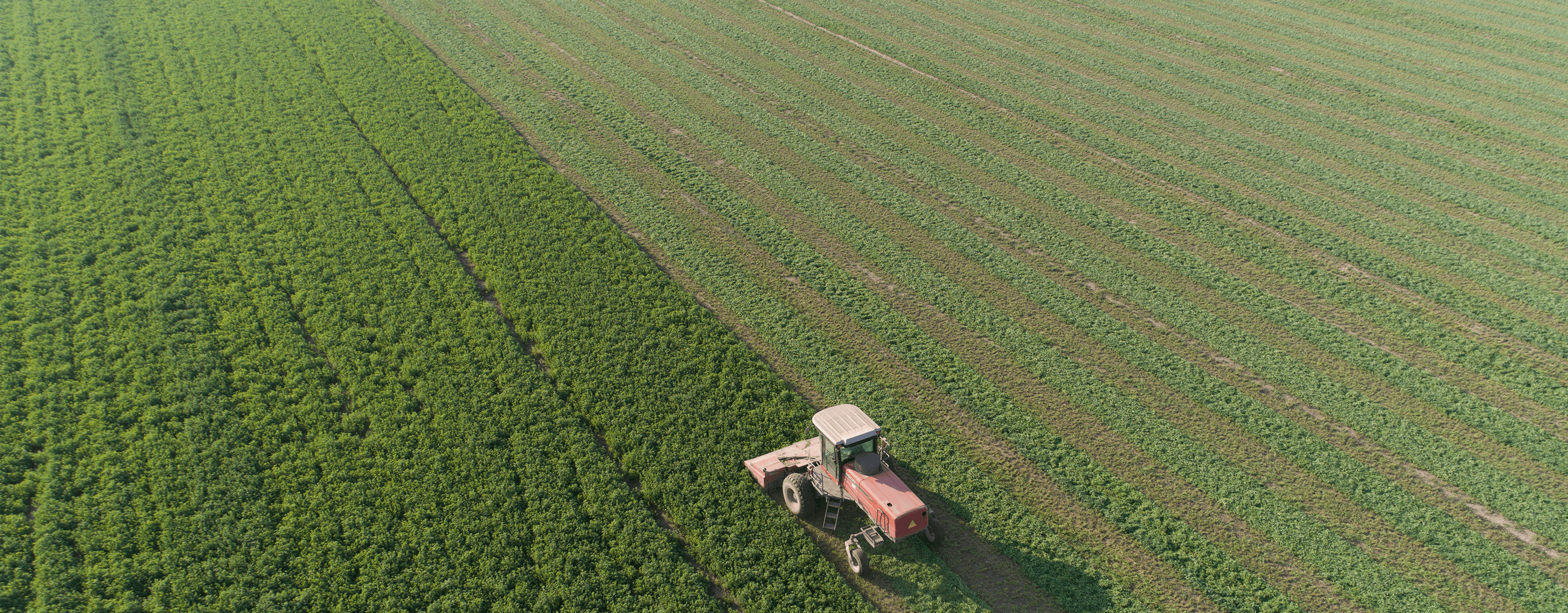 An Aerial View Of A Tractor In The Field Harvesting