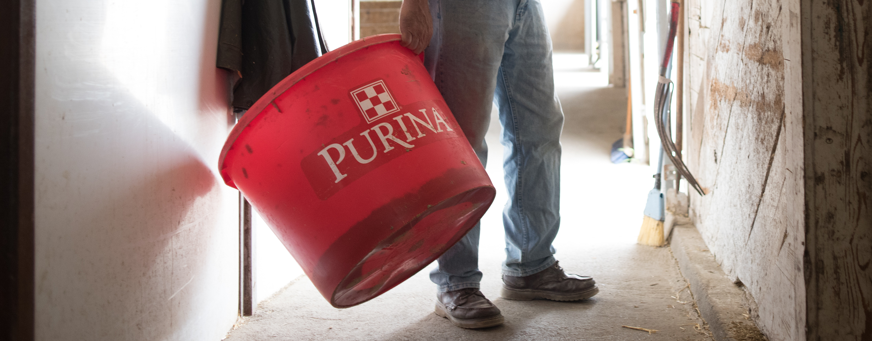 Person holding a red Purina feed tub