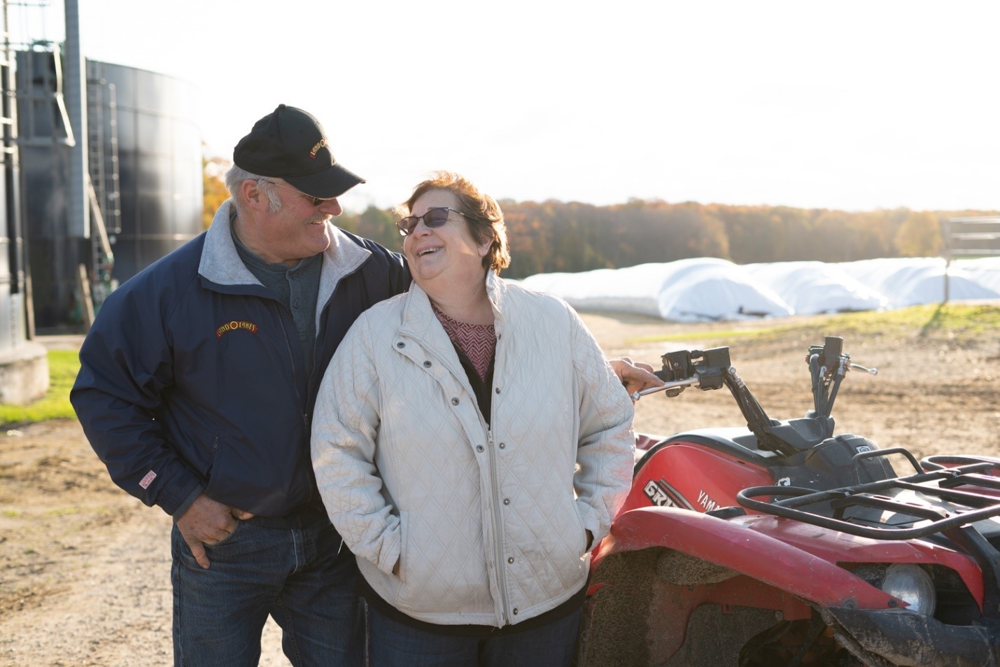 Photo of Deb and Ed Staats, with farm in background