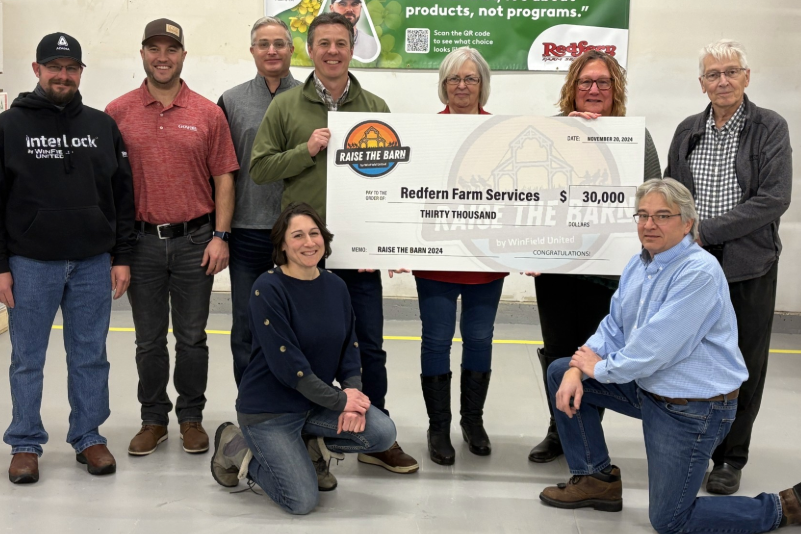 A group of people hold a novelty sized check for charity.