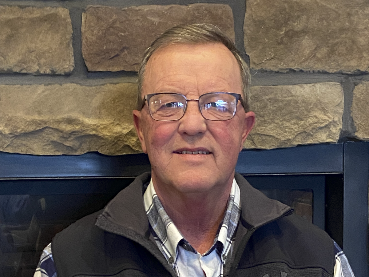 A man poses in front of a brick wall
